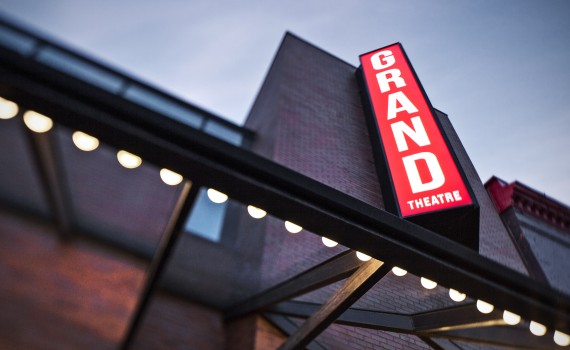 A view of the Grand Theatre's marquee lights at the front entrance, with a large sign that reads "GRAND" above.